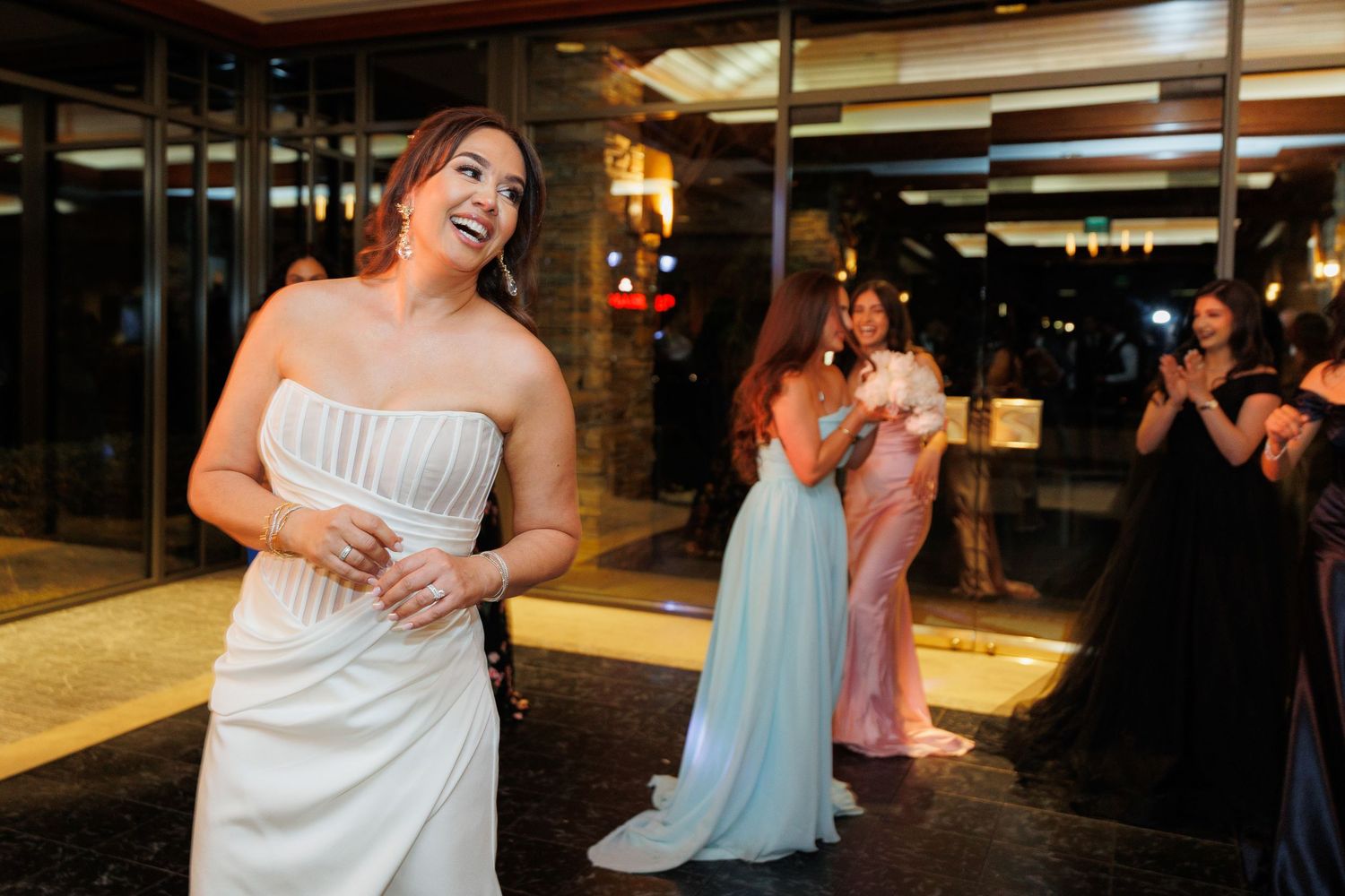 Wedding party guests dance and celebrate on a dimly lit dance floor at an evening reception.