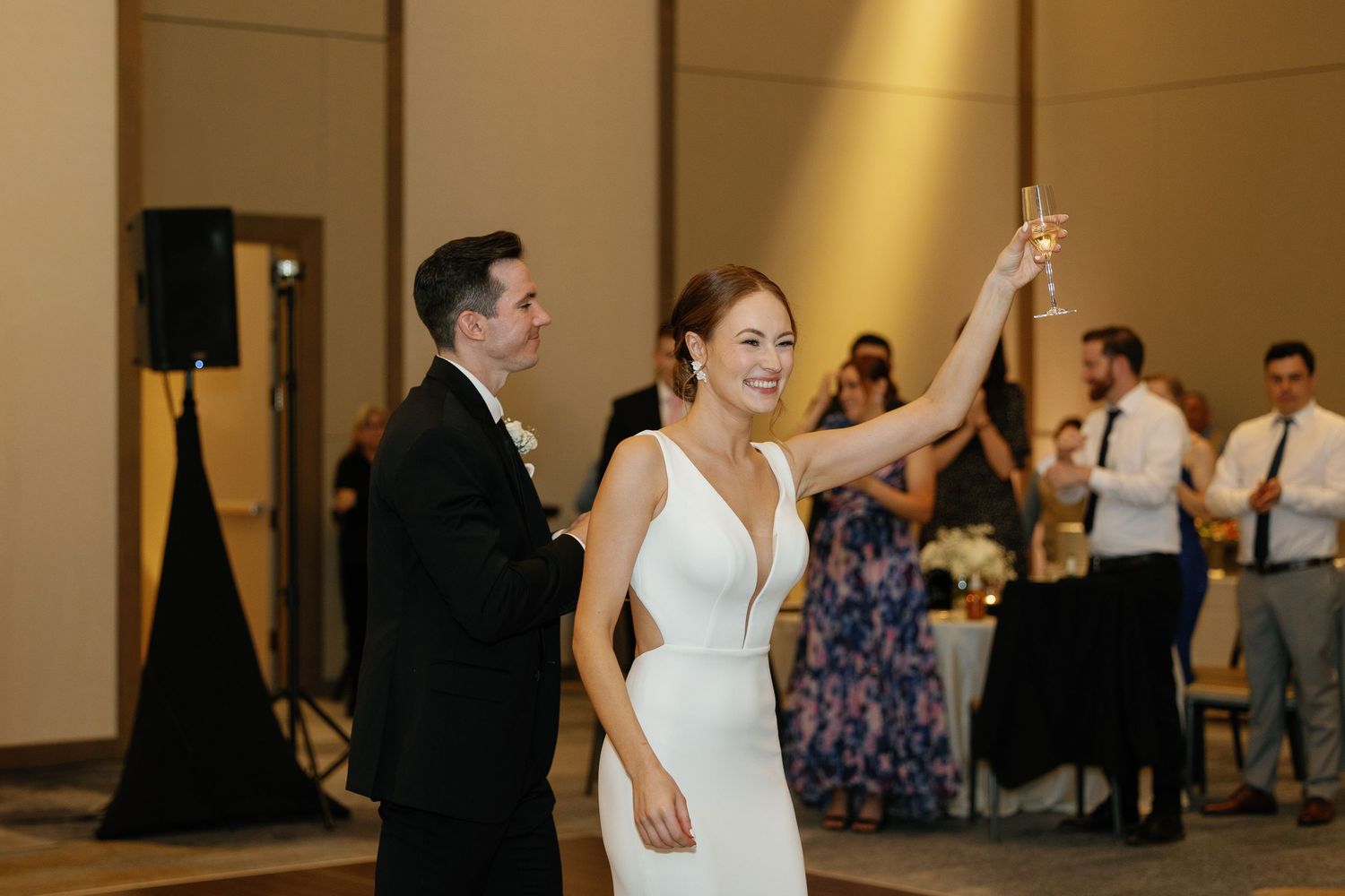 A couple performs an elegant dance move during a wedding reception in a warmly lit ballroom.