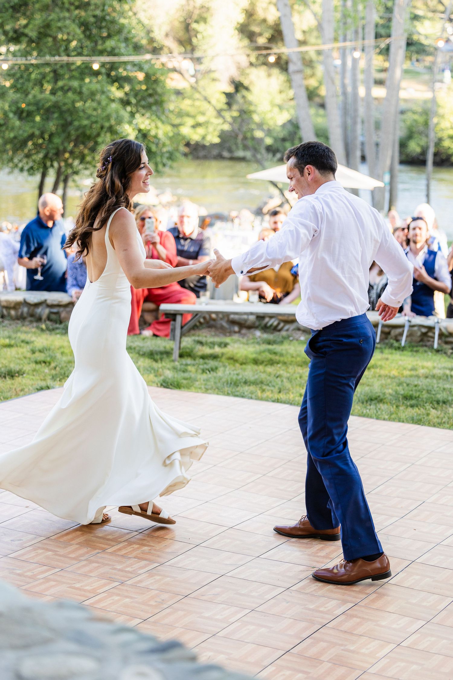 A couple dancing on an outdoor patio shows a sequence of energetic twirls in their elegant wedding attire.
