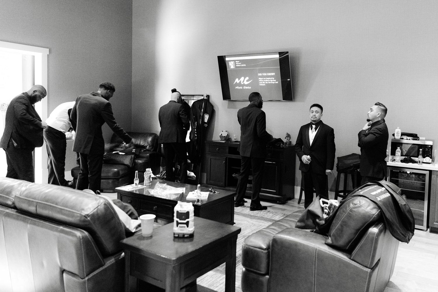 Black and white panoramic view of multiple business meetings happening simultaneously in office conference rooms.