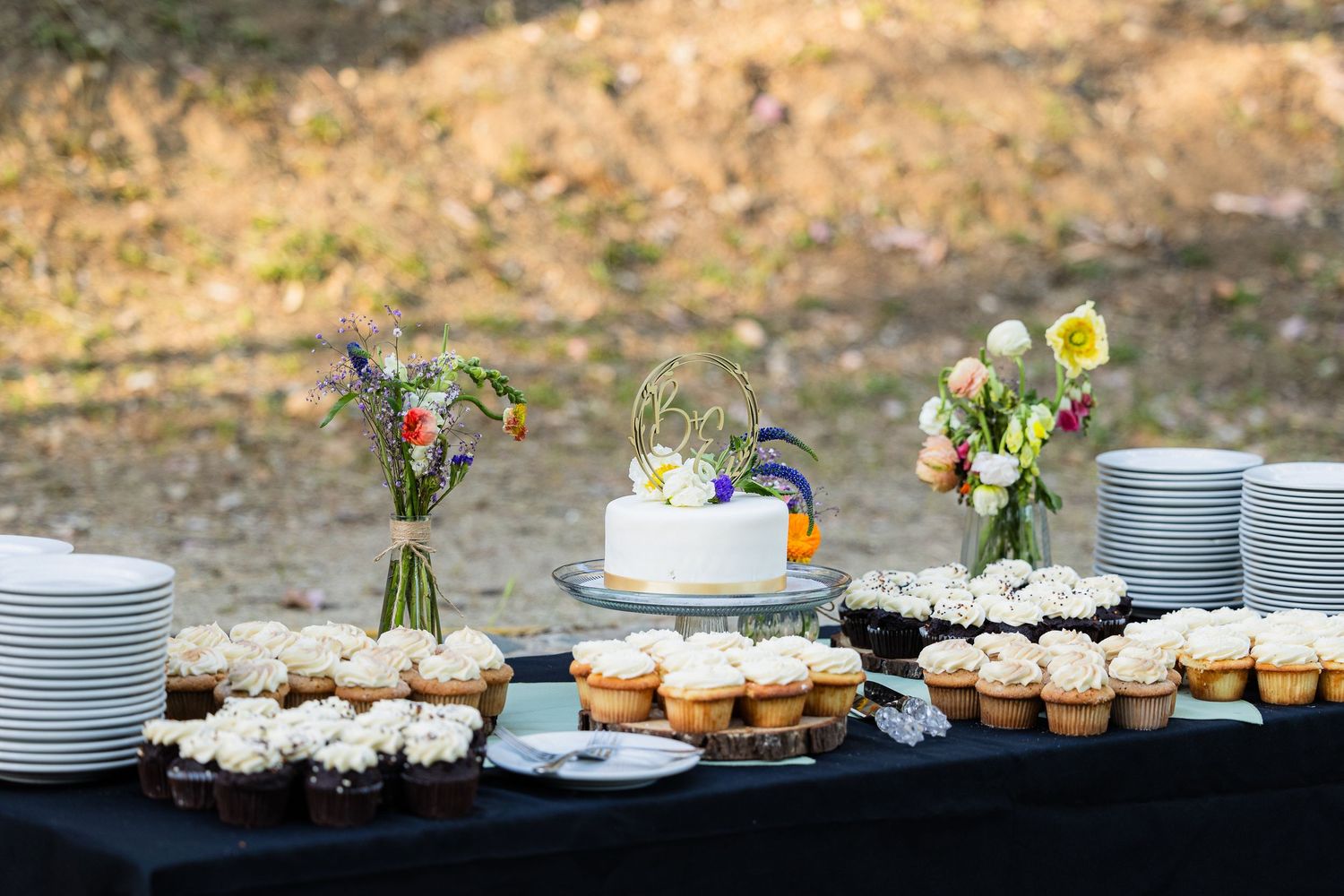 A long buffet table with white plates and elegant desserts arranged for a catered event or wedding reception.