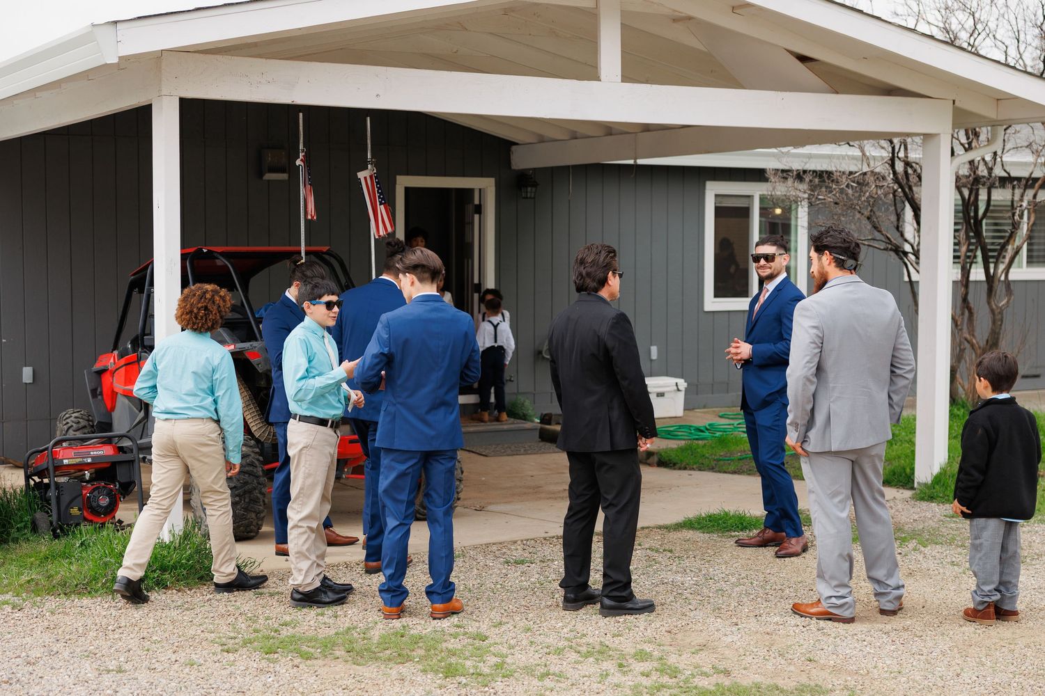 People stand in line outside a building with covered walkways during what appears to be a community gathering or event.