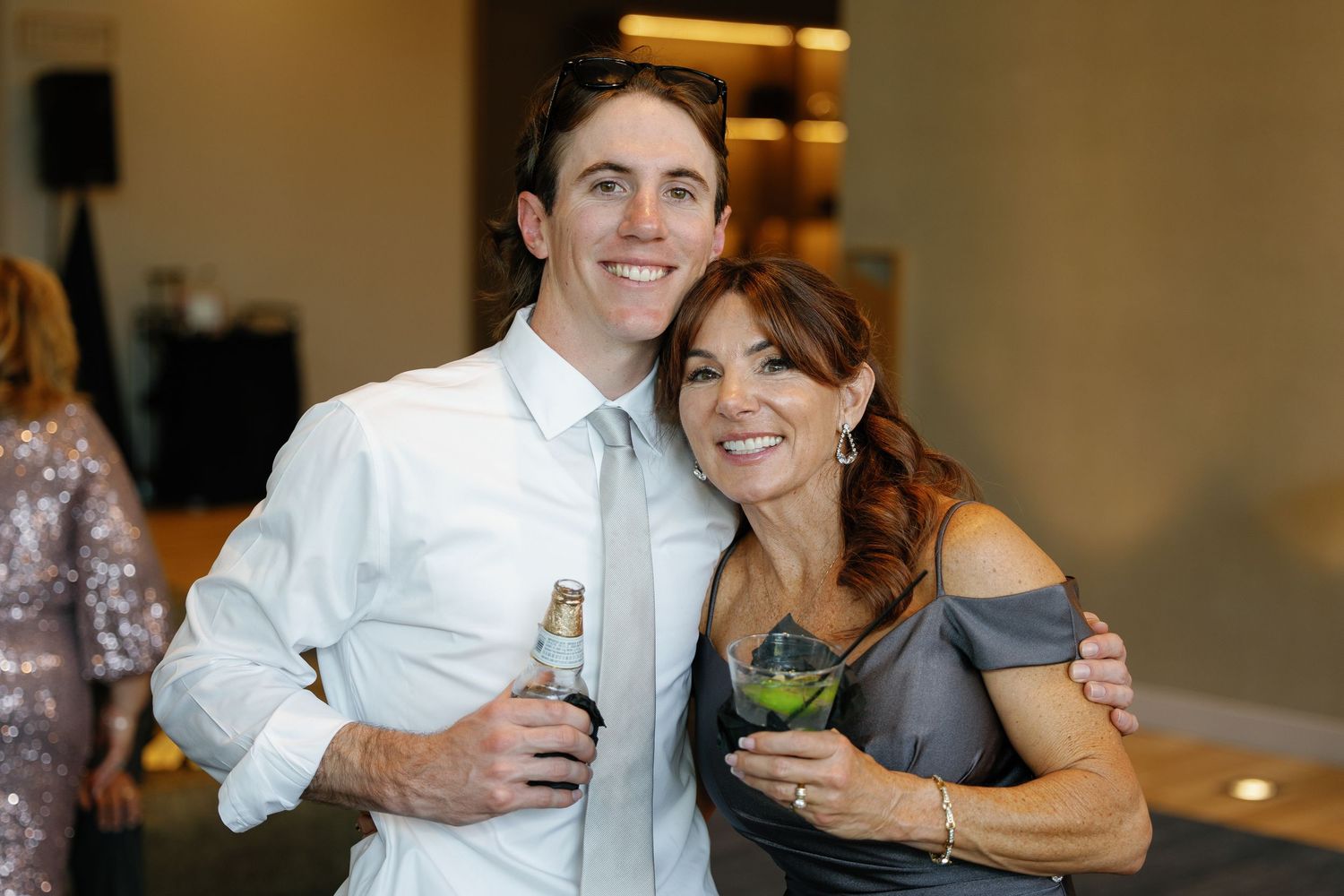 A couple shares laughter and cocktails during what appears to be a wedding reception or celebration.