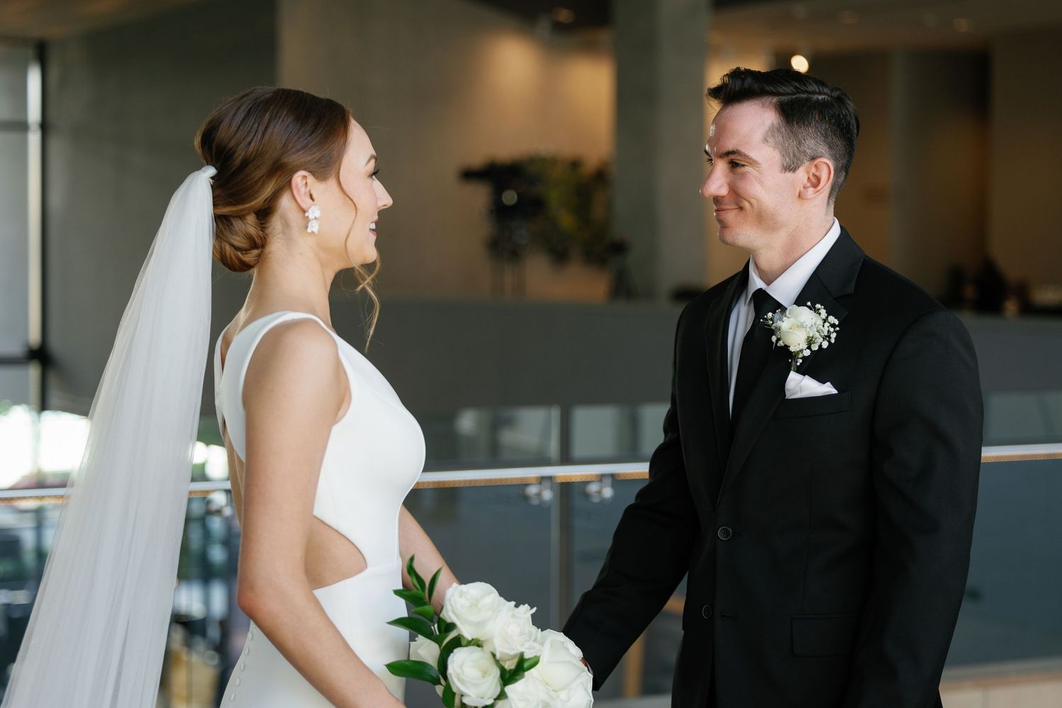 A bride and groom share a tender moment during their wedding ceremony in an elegant indoor venue.
