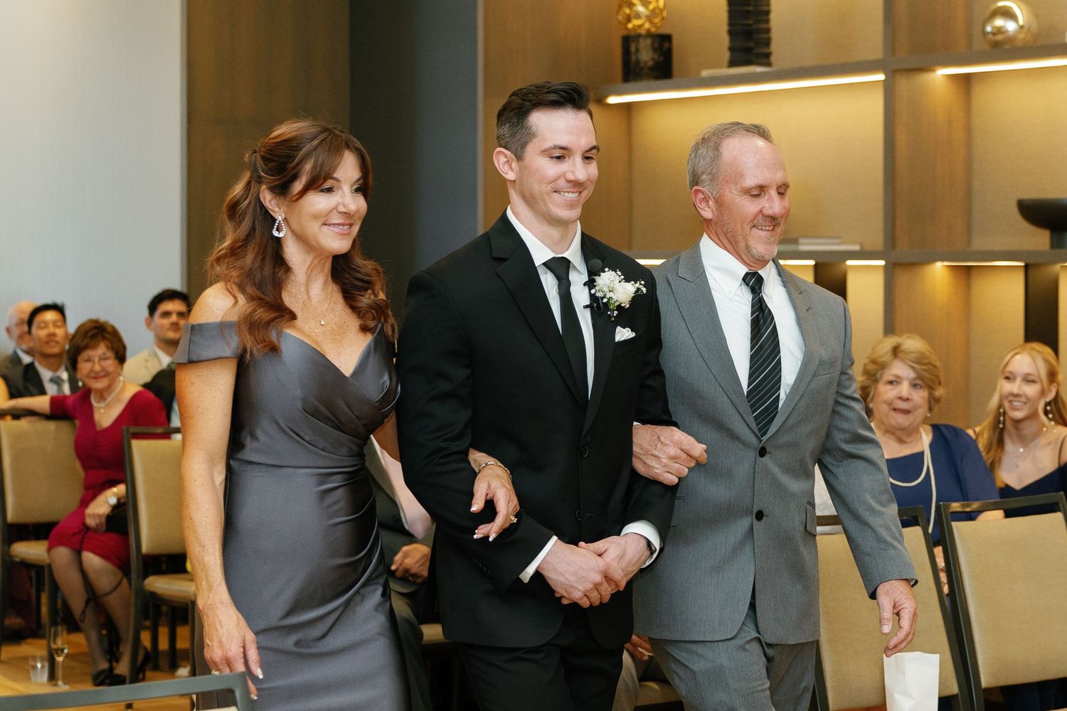 A group of wedding guests dancing and celebrating together on the dance floor at an indoor reception venue.