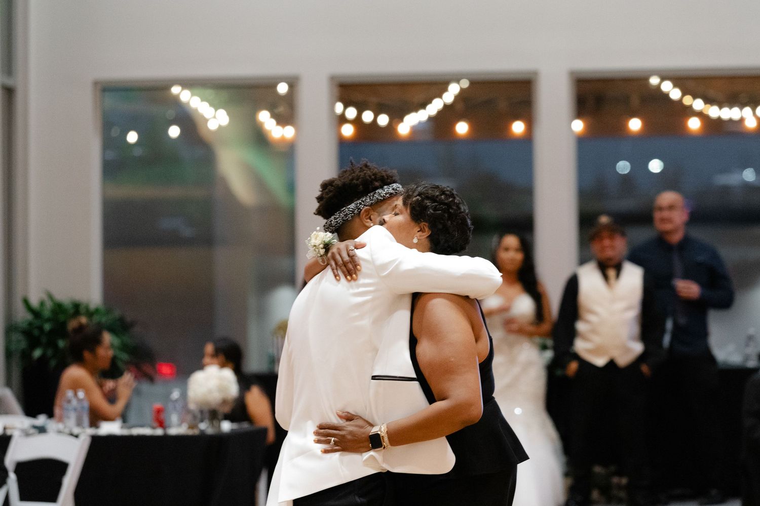 Couples dance together in an elegant indoor venue decorated with string lights during a wedding reception.