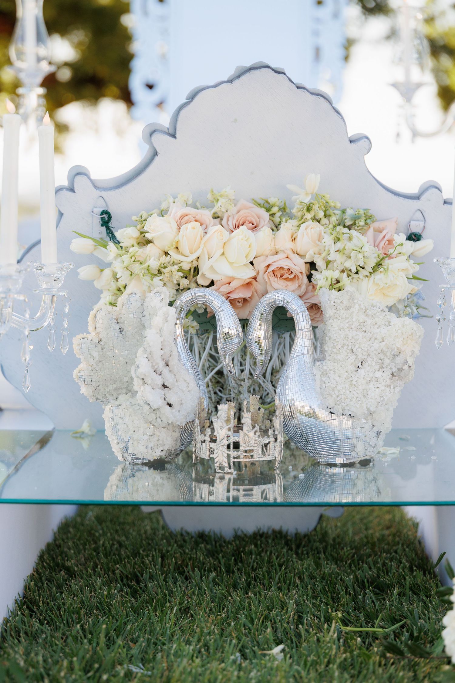 Elegant wedding centerpiece arrangement of white hydrangeas and blush roses in silver mercury glass vases on glass table.