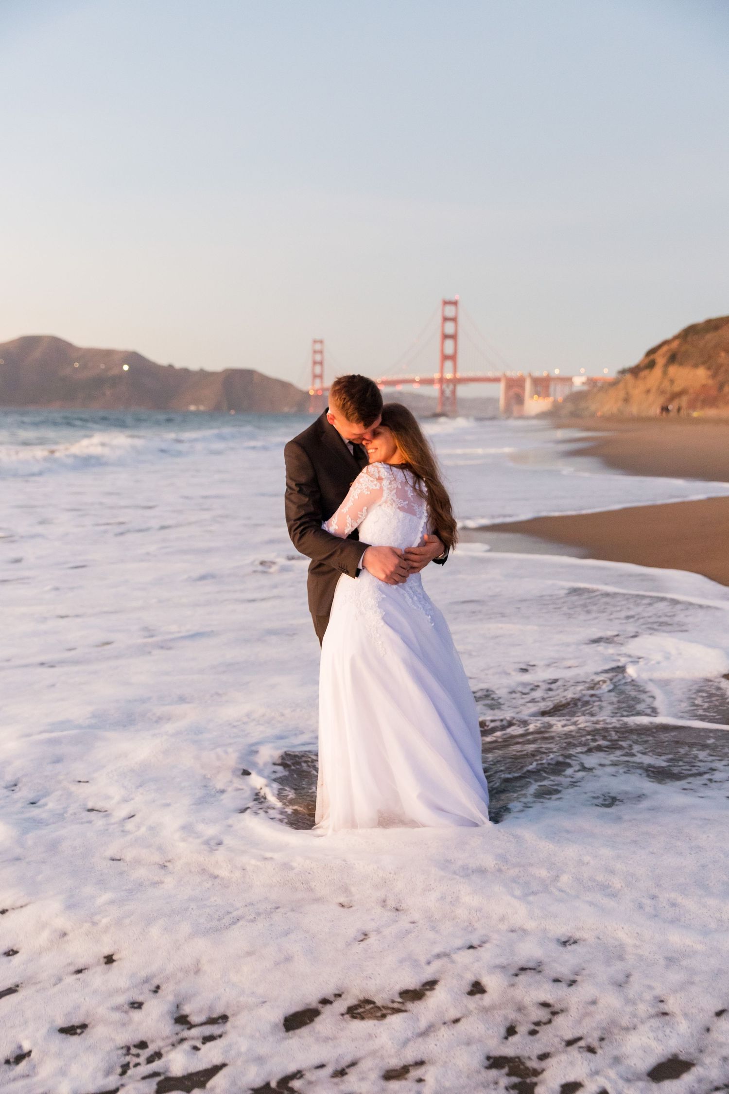 Beach wedding photos at Baker Beach with the Golden Gate Bridge visible in the background.