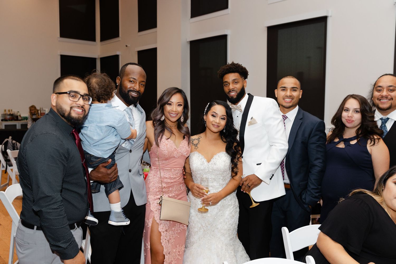 A group of wedding guests dancing and celebrating together at an elegant indoor reception venue.