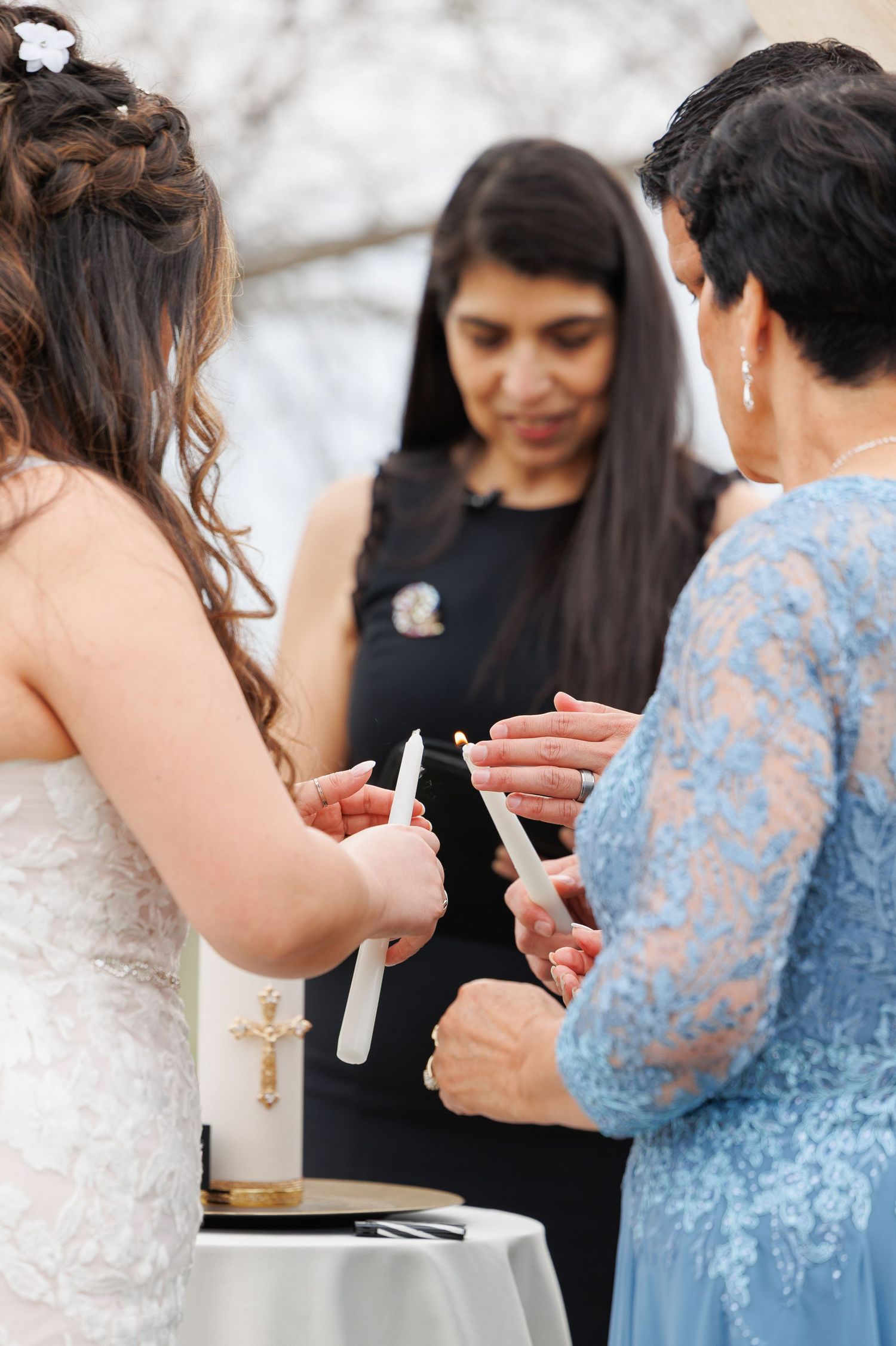 Wedding ceremony participants pour sand into a unity vessel during an intimate outdoor ceremony ritual.