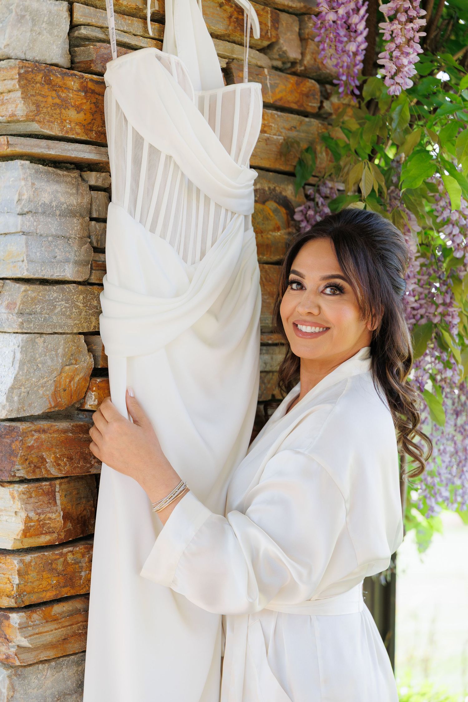 A series of photos showing a white flowy dress against a stone wall with purple wisteria flowers in the background.