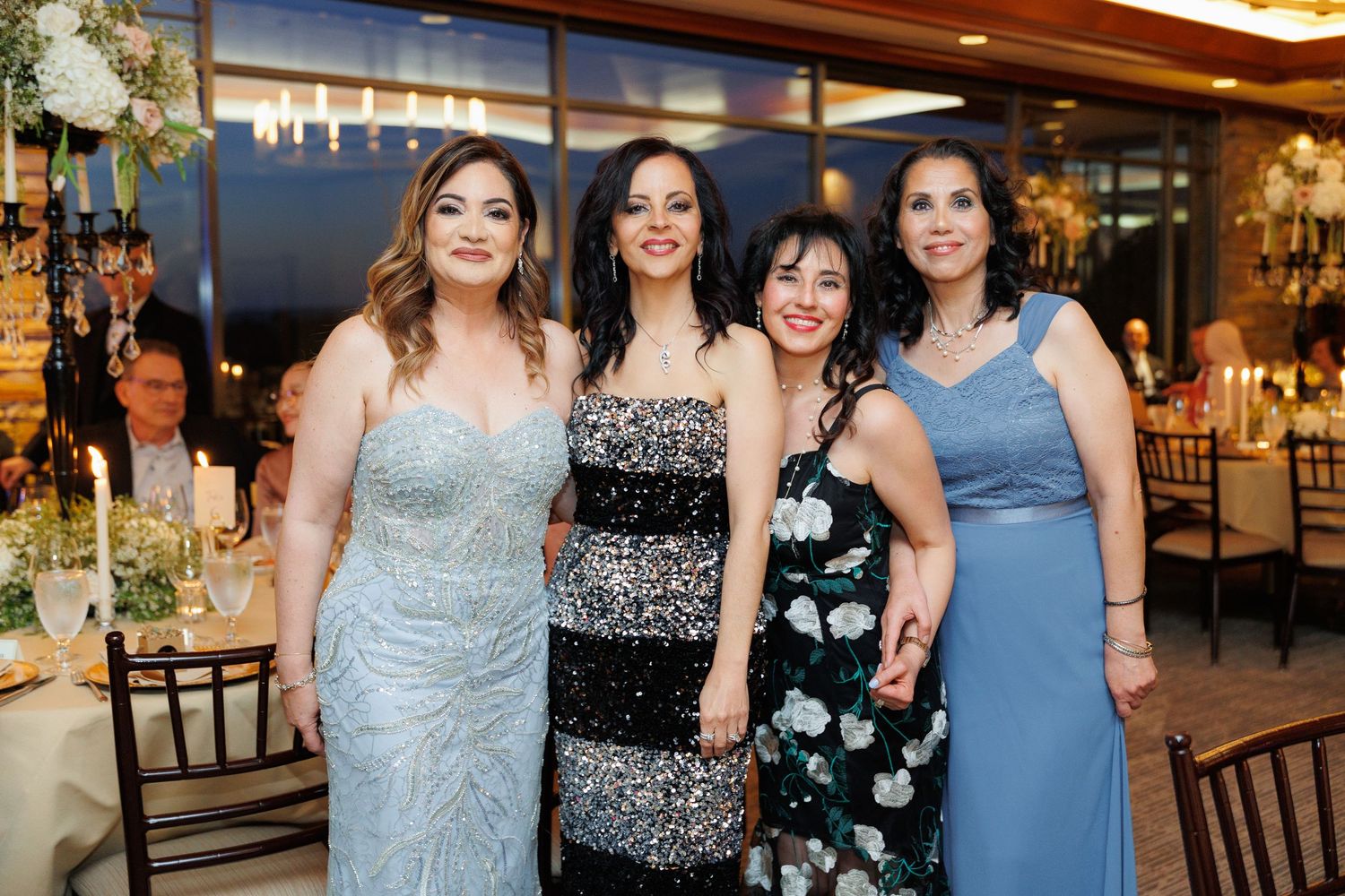A group wearing blue and patterned dresses poses together at an elegant indoor event.