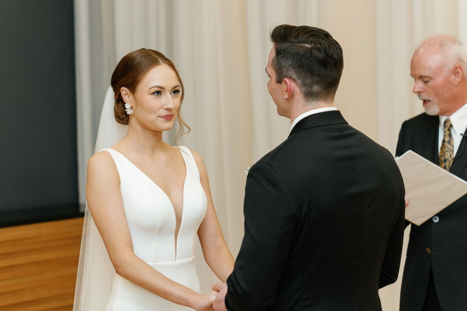 A couple shares an intimate dance moment at their wedding reception on a wooden dance floor.