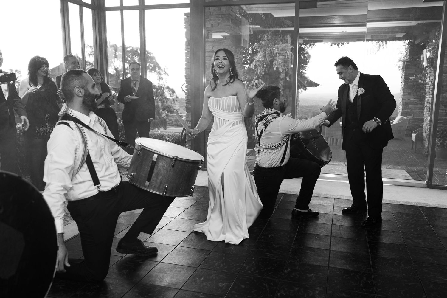 Wedding guests dance and celebrate on a black and white dance floor during an evening reception.