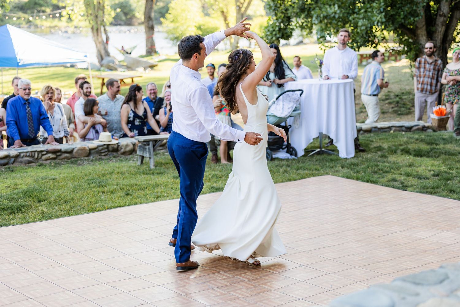 Couple dancing together on an outdoor patio during a wedding celebration in a scenic garden setting.