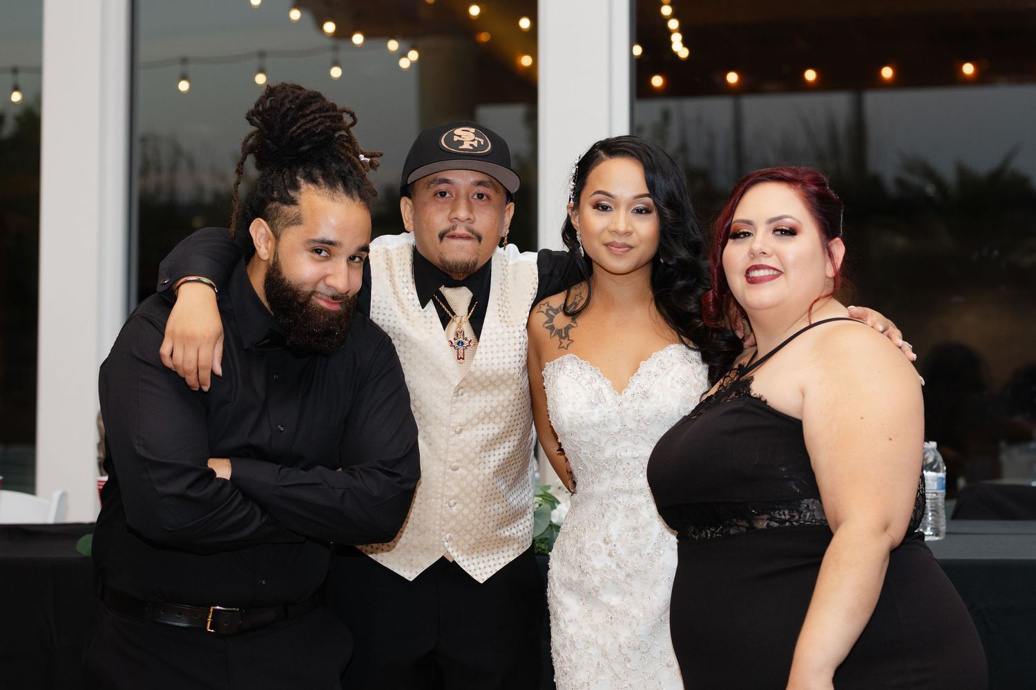 A wedding party poses together at an evening reception in formal black and white attire.