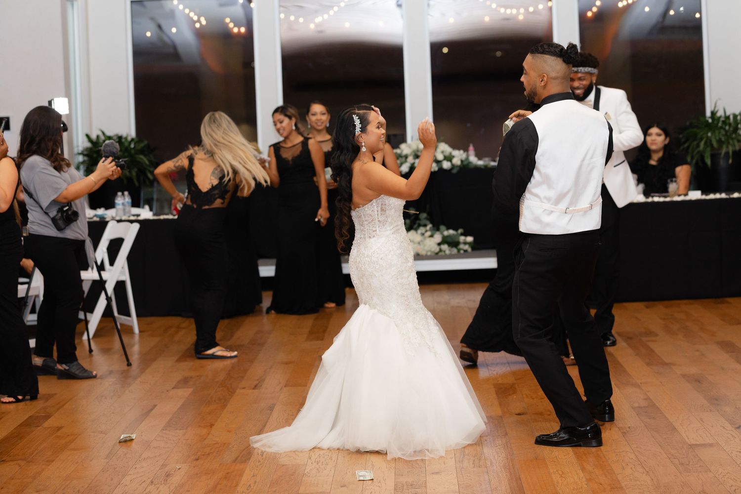 Wedding guests dancing and celebrating on a wooden dance floor during a wedding reception.