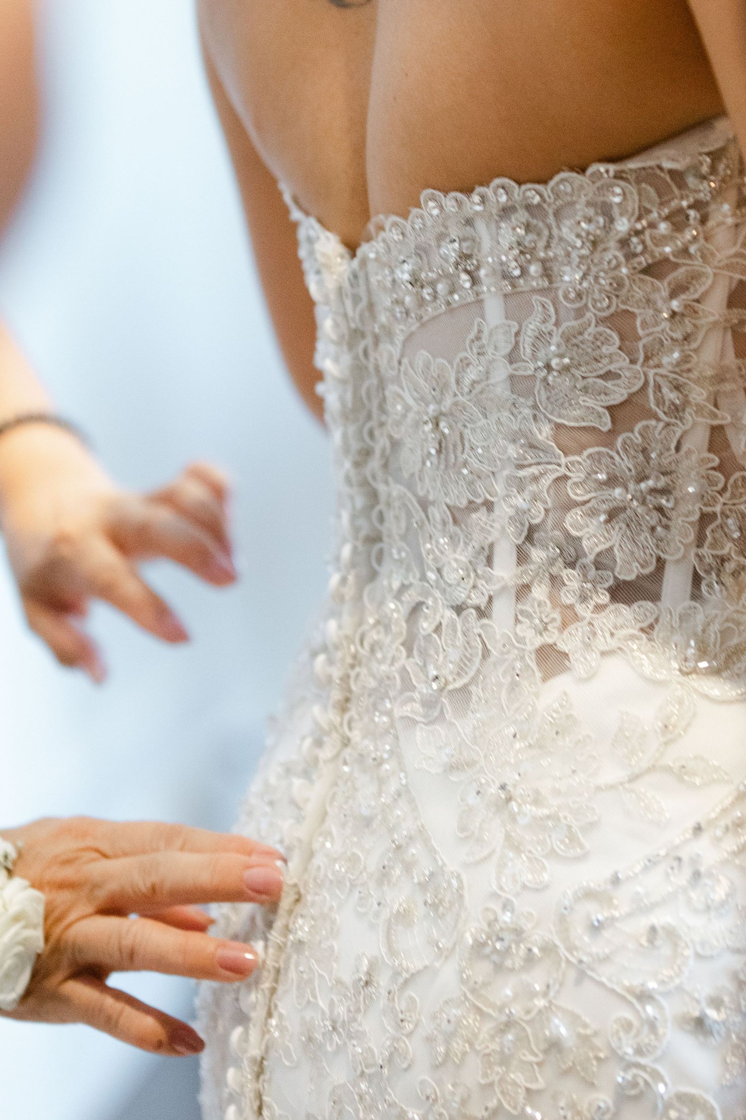 Close-up detail of intricate white lace and beading on a wedding dress bodice.