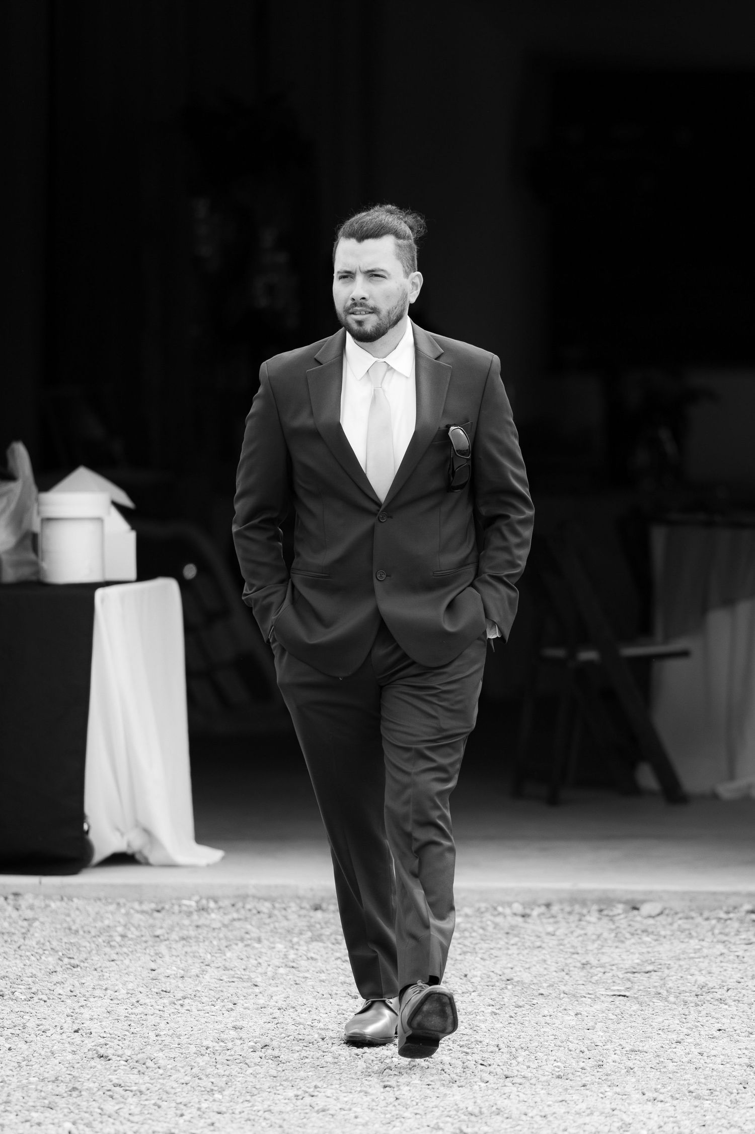A black and white photo sequence shows a person in a formal tuxedo walking across a gravel or stone surface.