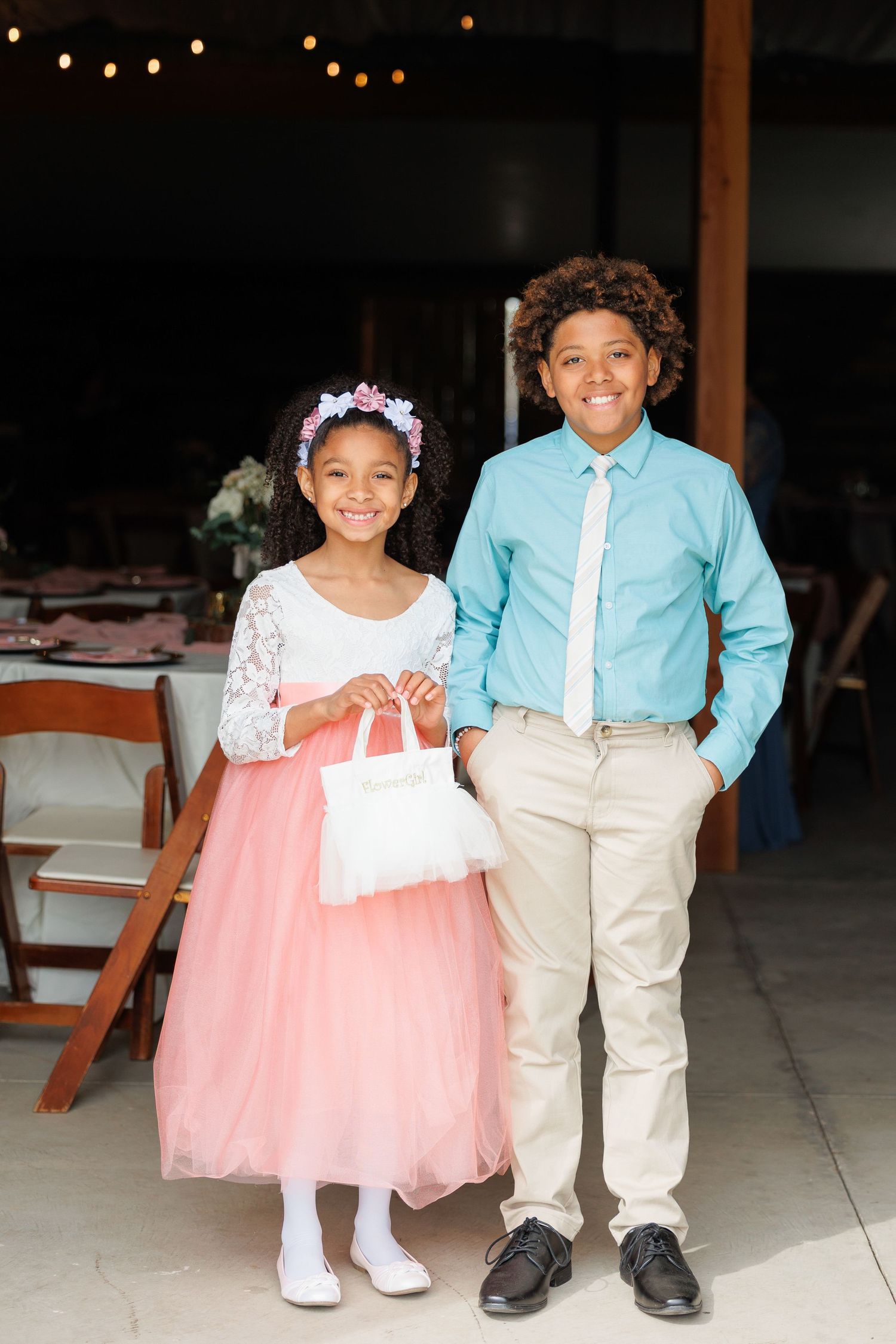 Two young children in coordinating pink and blue formal attire pose together at a special event.