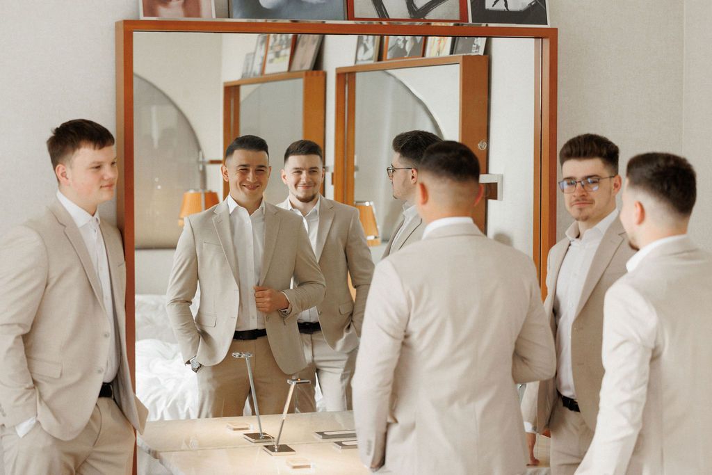 Several people in coordinated cream suits standing together in front of mirrored closet doors.