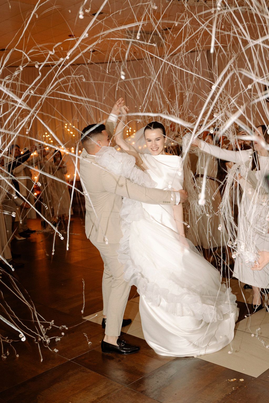 Couple dancing at wedding reception with white streamers and sparklers creating magical celebratory atmosphere.