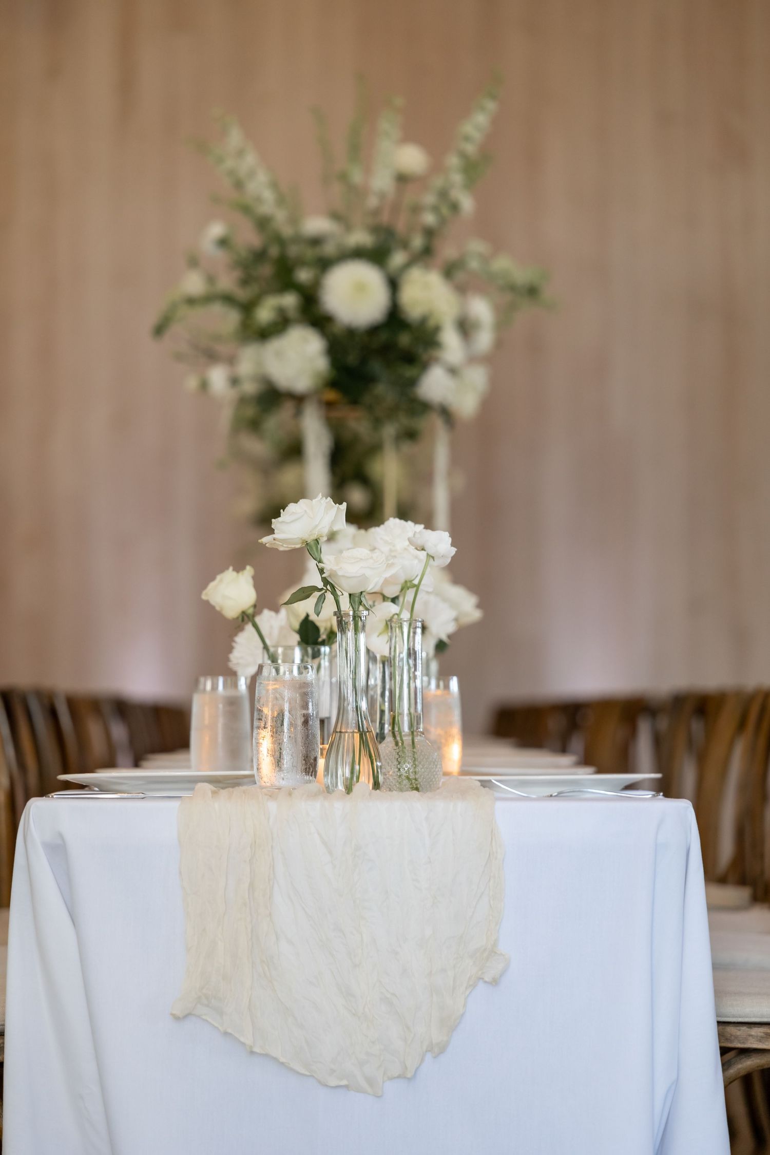 White floral centerpieces and candles decorate elegant wedding reception tables.