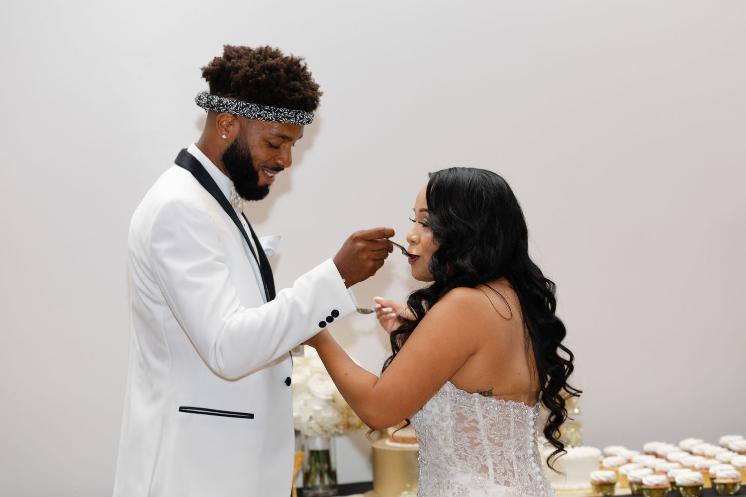 A couple shares an intimate moment during their wedding reception while enjoying cake and champagne together.