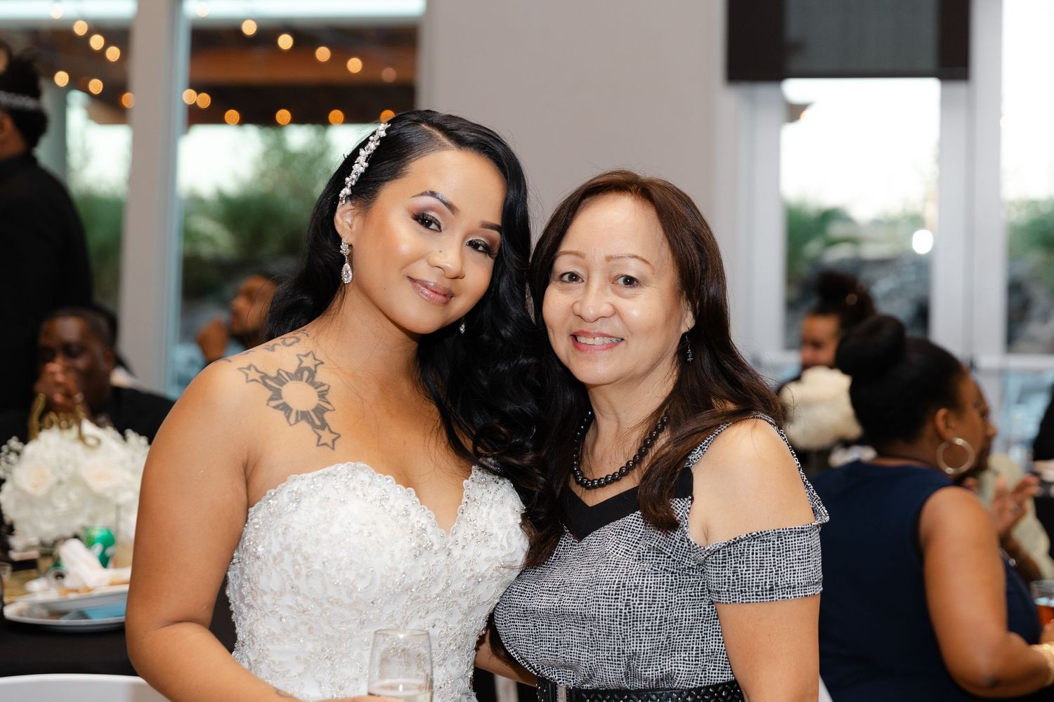 Two people smile together at a formal event with glittering lights in the background.