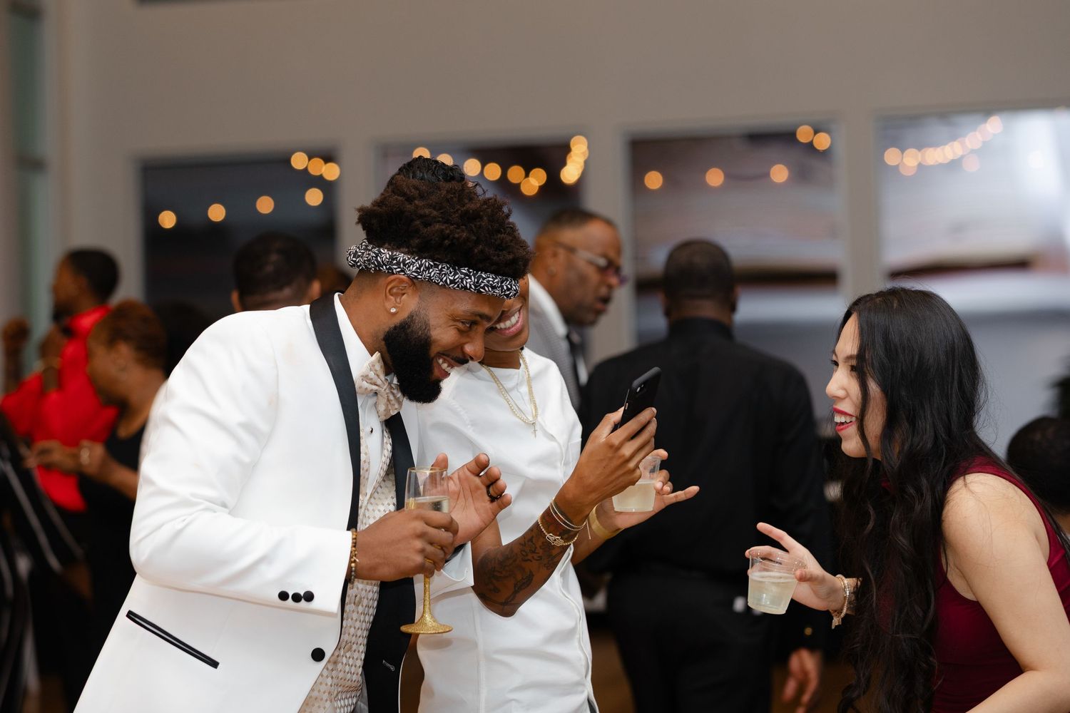 A group of wedding guests share emotional reactions during a reception celebration.