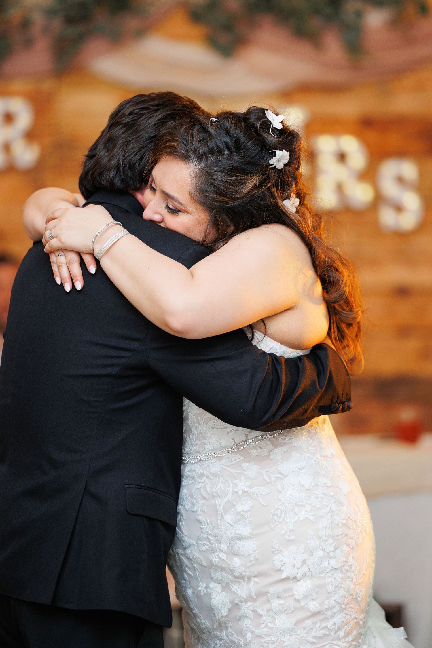 A series of wedding photos showing close embraces between a couple in formal attire against a rustic wooden backdrop.