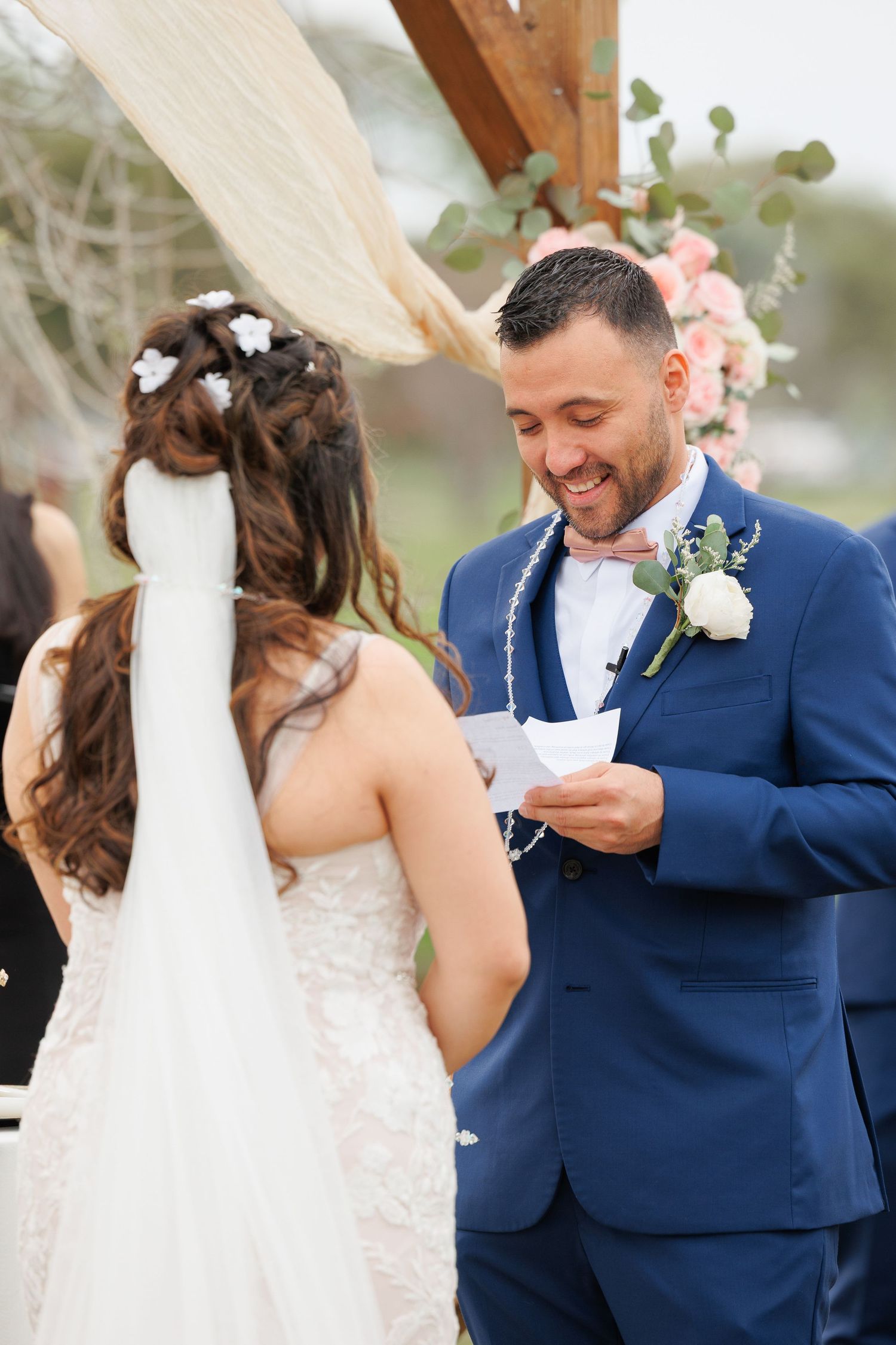A couple shares an emotional moment during their wedding ceremony with the bride in white and groom in navy blue suit.