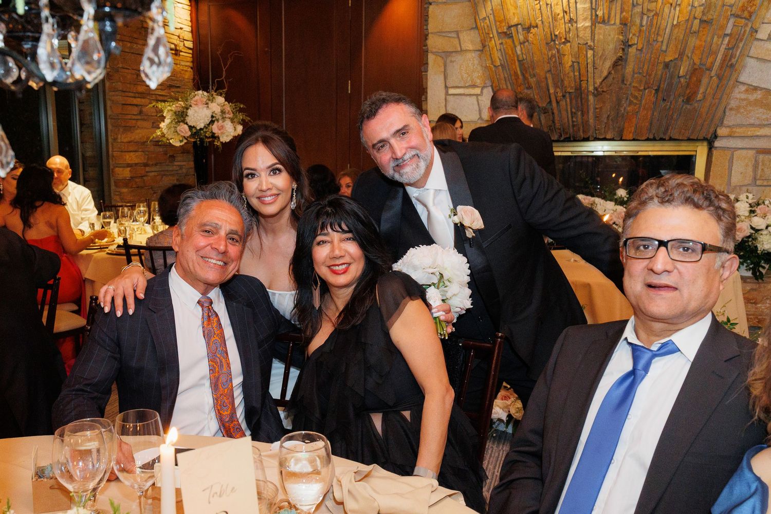 Guests enjoying a formal dinner event in an elegant restaurant setting with warm lighting and decorative chandeliers.