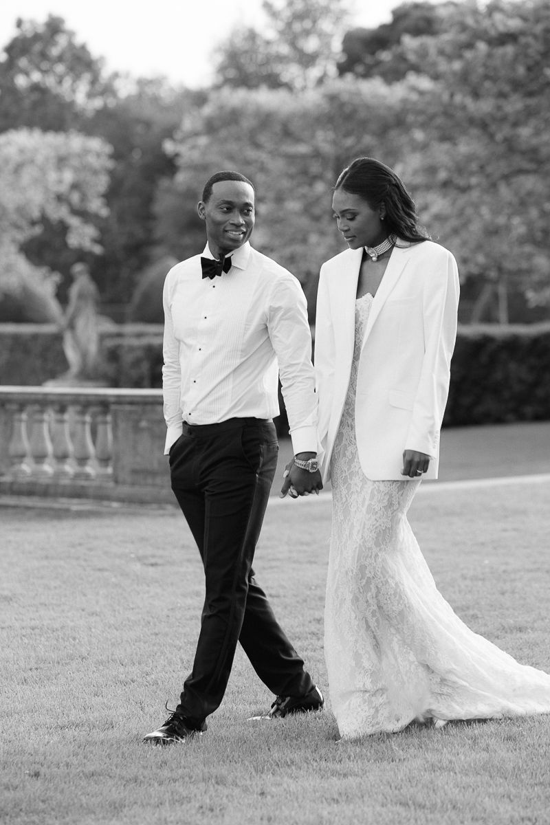 A black and white photo captures a couple walking together on their wedding day.