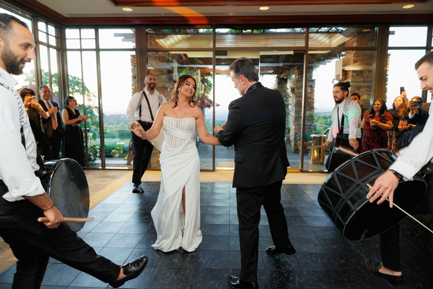 Newlyweds share their first dance at a modern venue while guests watch from the perimeter of the dance floor.