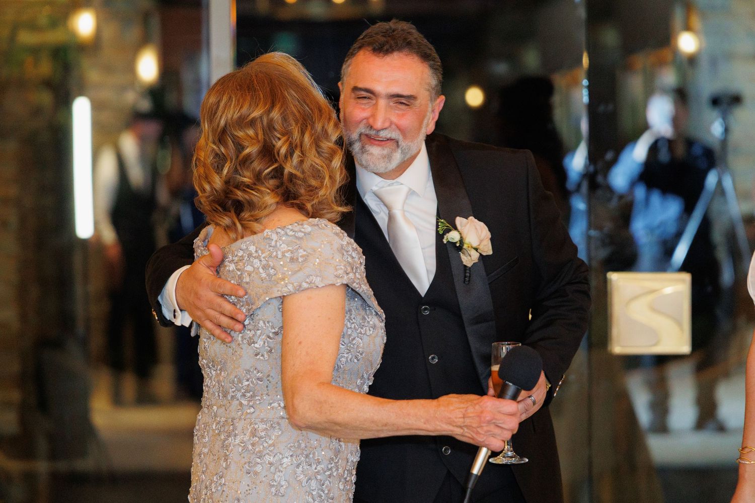 Couple in formal attire sharing a dance together at an elegant indoor venue with warm lighting.