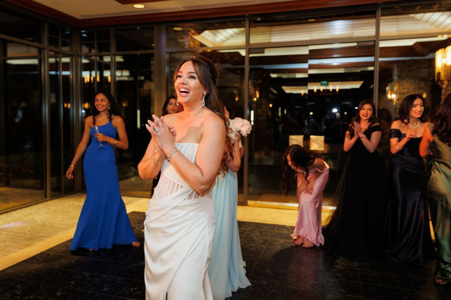 Wedding guests dance and celebrate on a dimly lit dance floor at an evening reception party.
