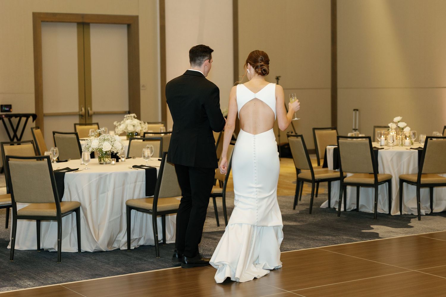 Reception hall decorated with round tables, gold chairs, and white linens for an elegant wedding celebration.
