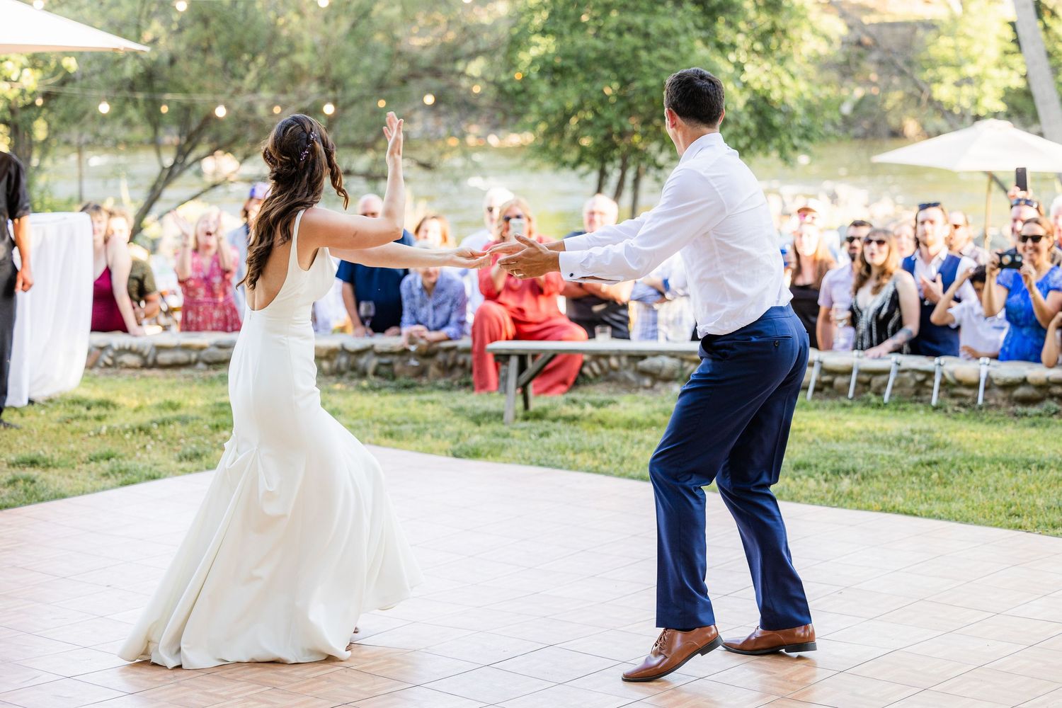 Wedding couple dances together on an outdoor stone patio during their first dance celebration.