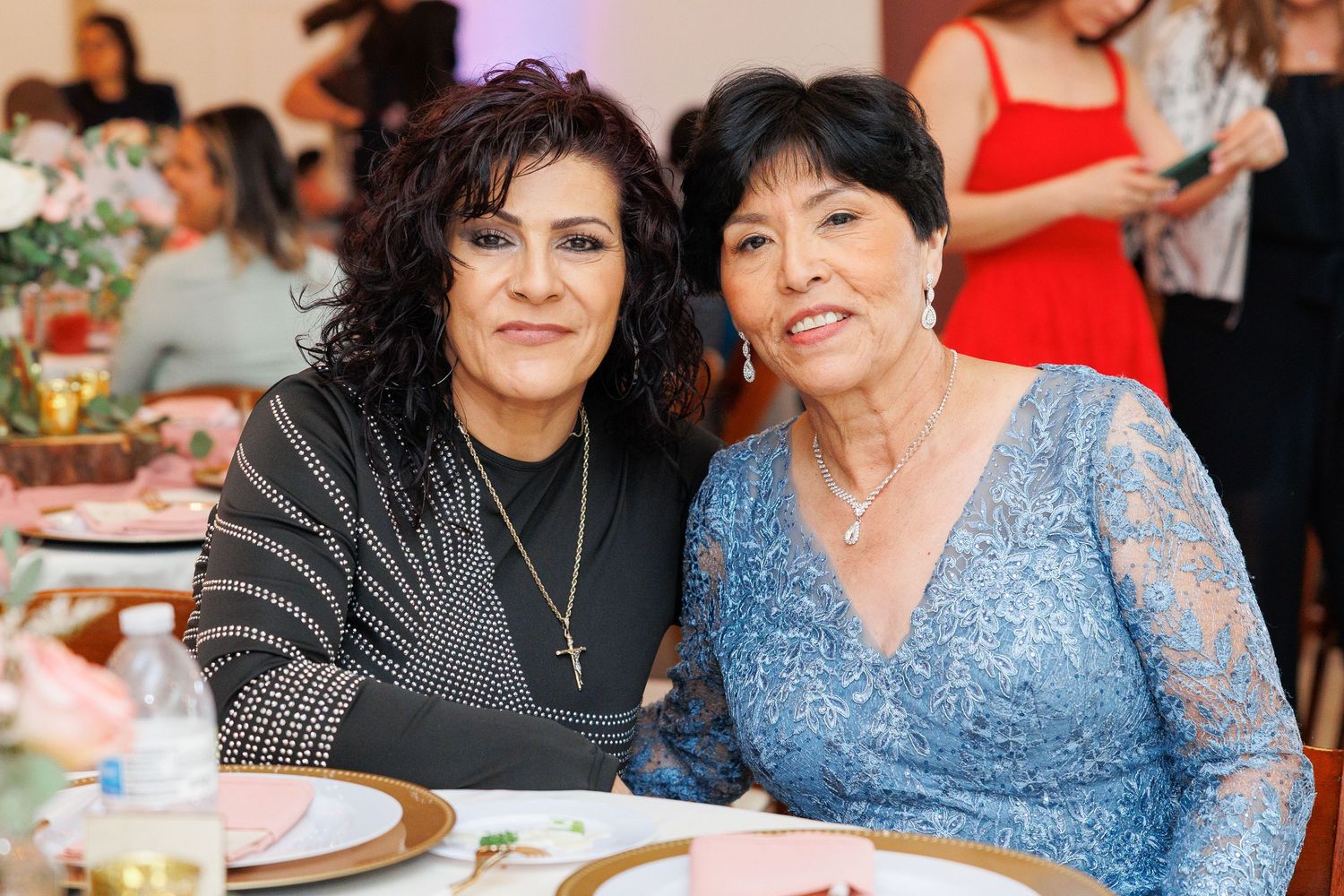 A family celebrates together at a special occasion wearing blue and red outfits while sitting at tables.