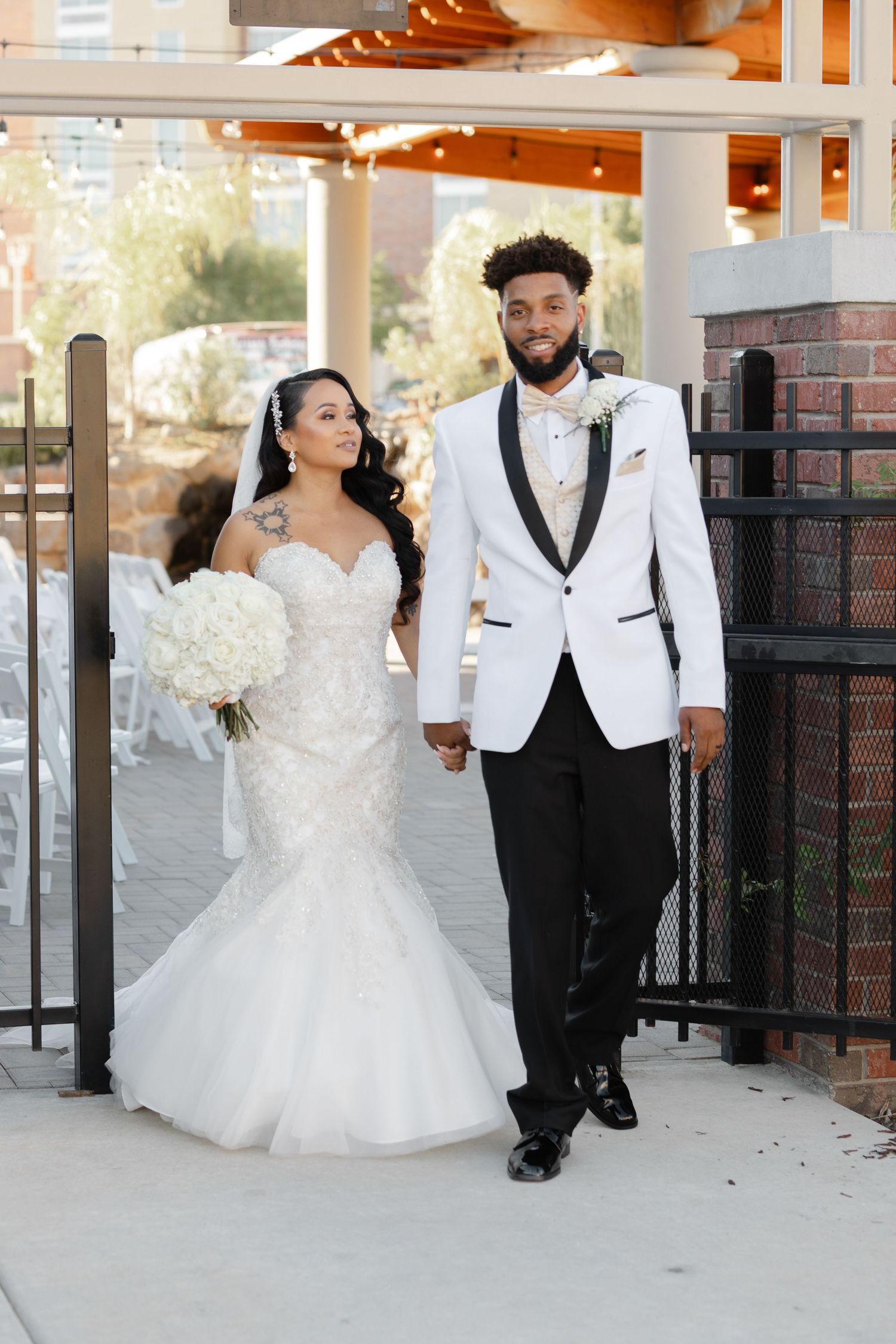 A bride in a white ballgown and groom in white tuxedo jacket share romantic wedding moments in outdoor portraits.