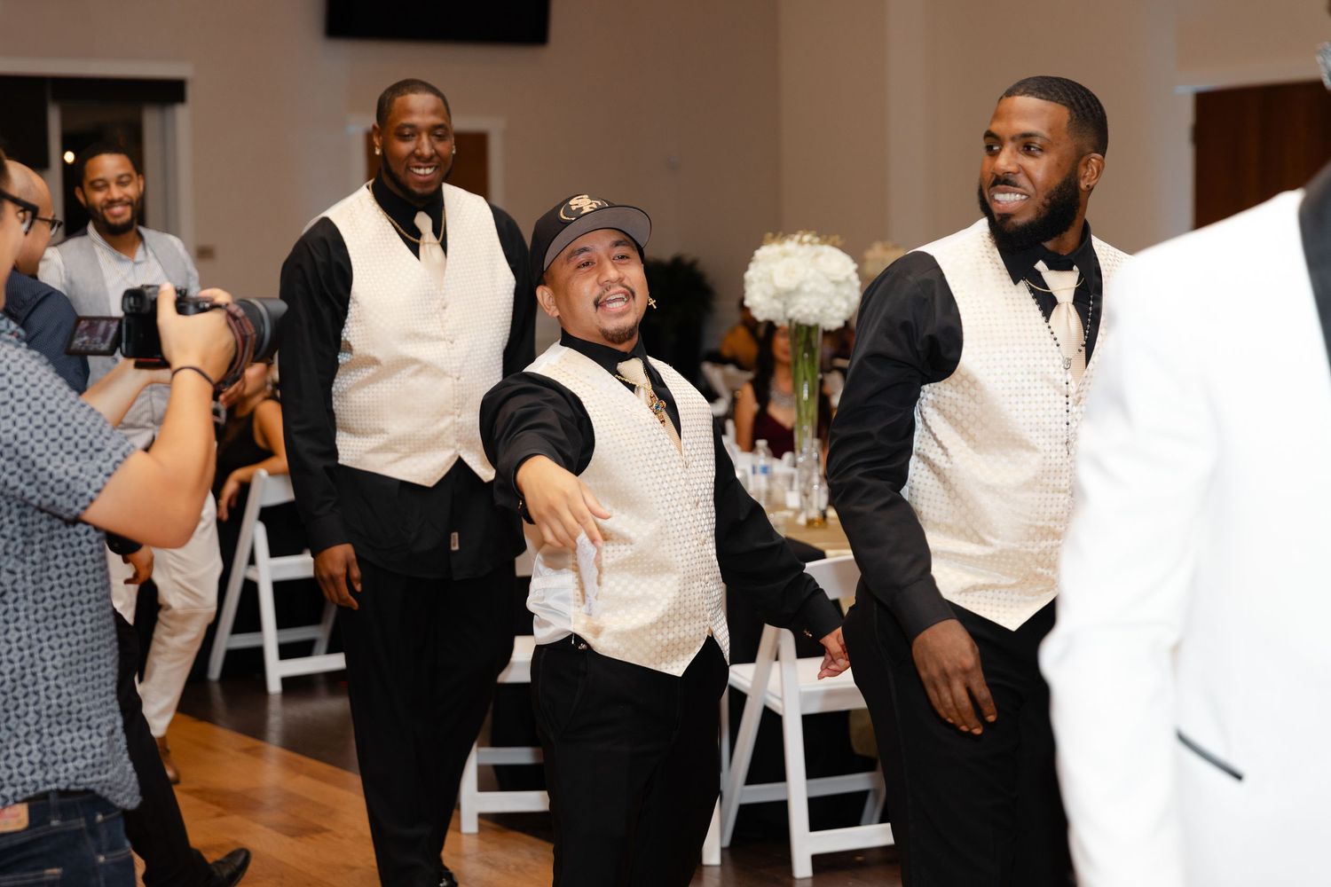 Wedding guests dance and celebrate together on the dance floor at an indoor reception venue.