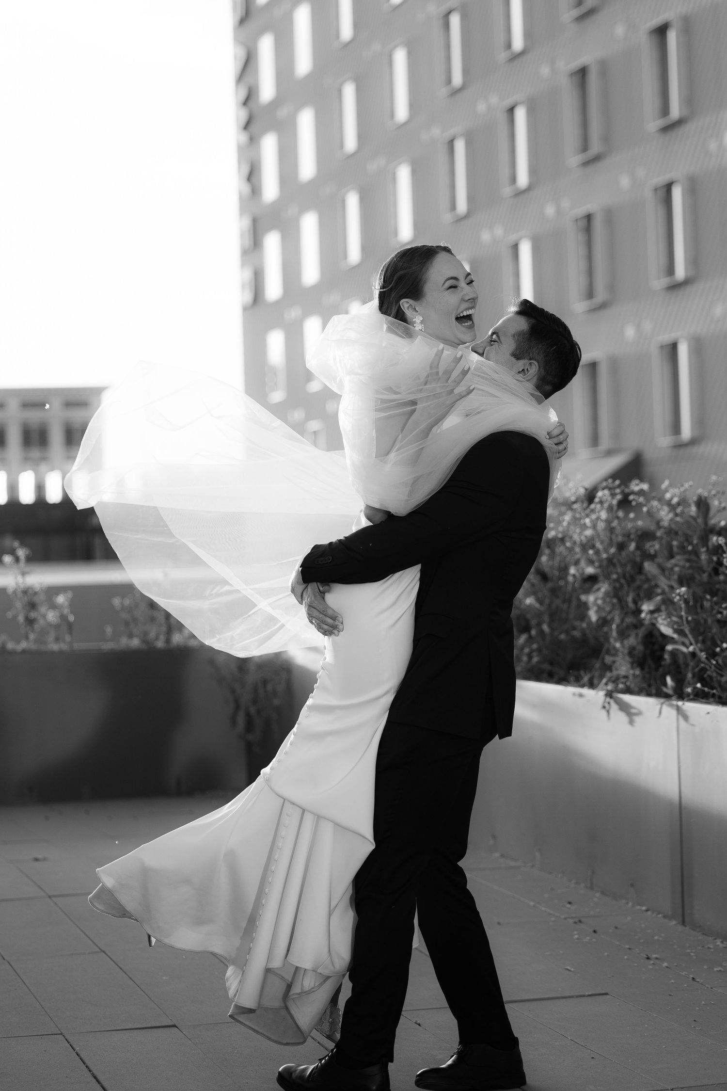 A romantic black and white photo series captures a couple dancing and twirling together on a rooftop.