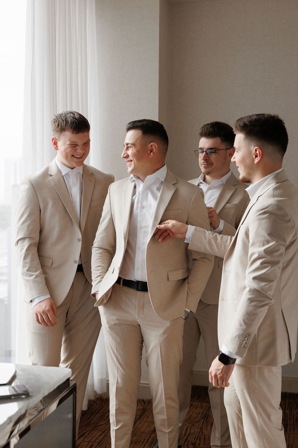 A group wearing matching light colored suits and white shirts gathered together in a bright room.
