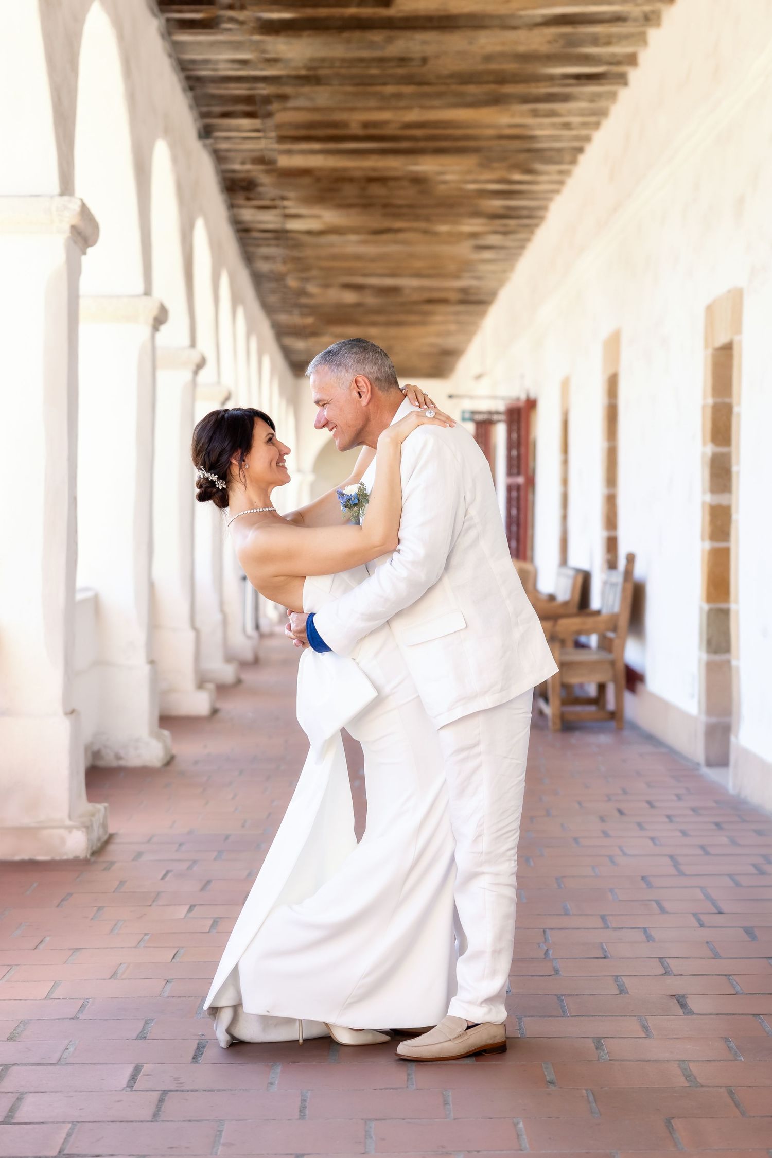 A series of romantic dance poses captured under a beautiful columned walkway with terracotta flooring.