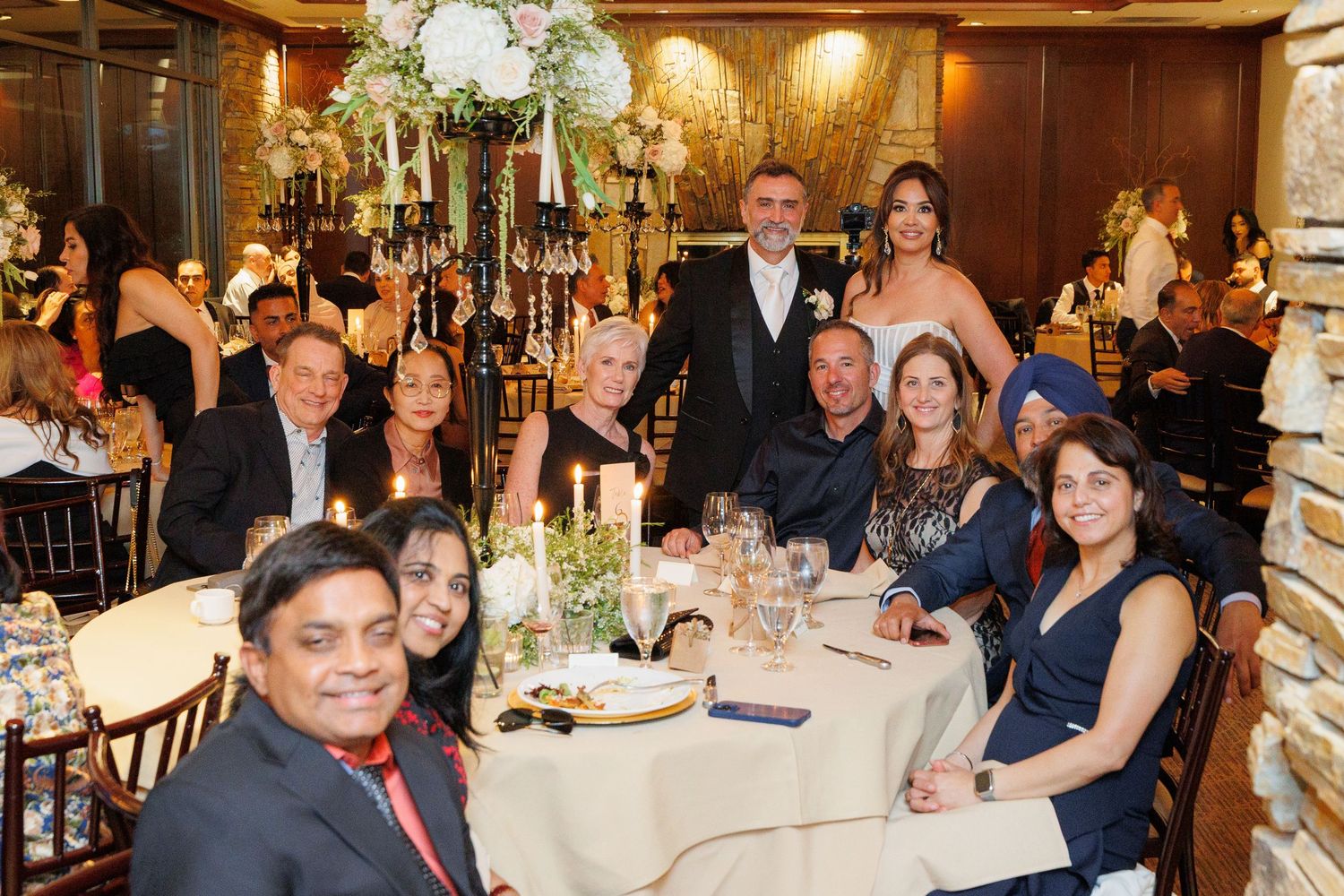 A group of people enjoying a formal dinner event at a restaurant with elegant table settings and warm lighting.
