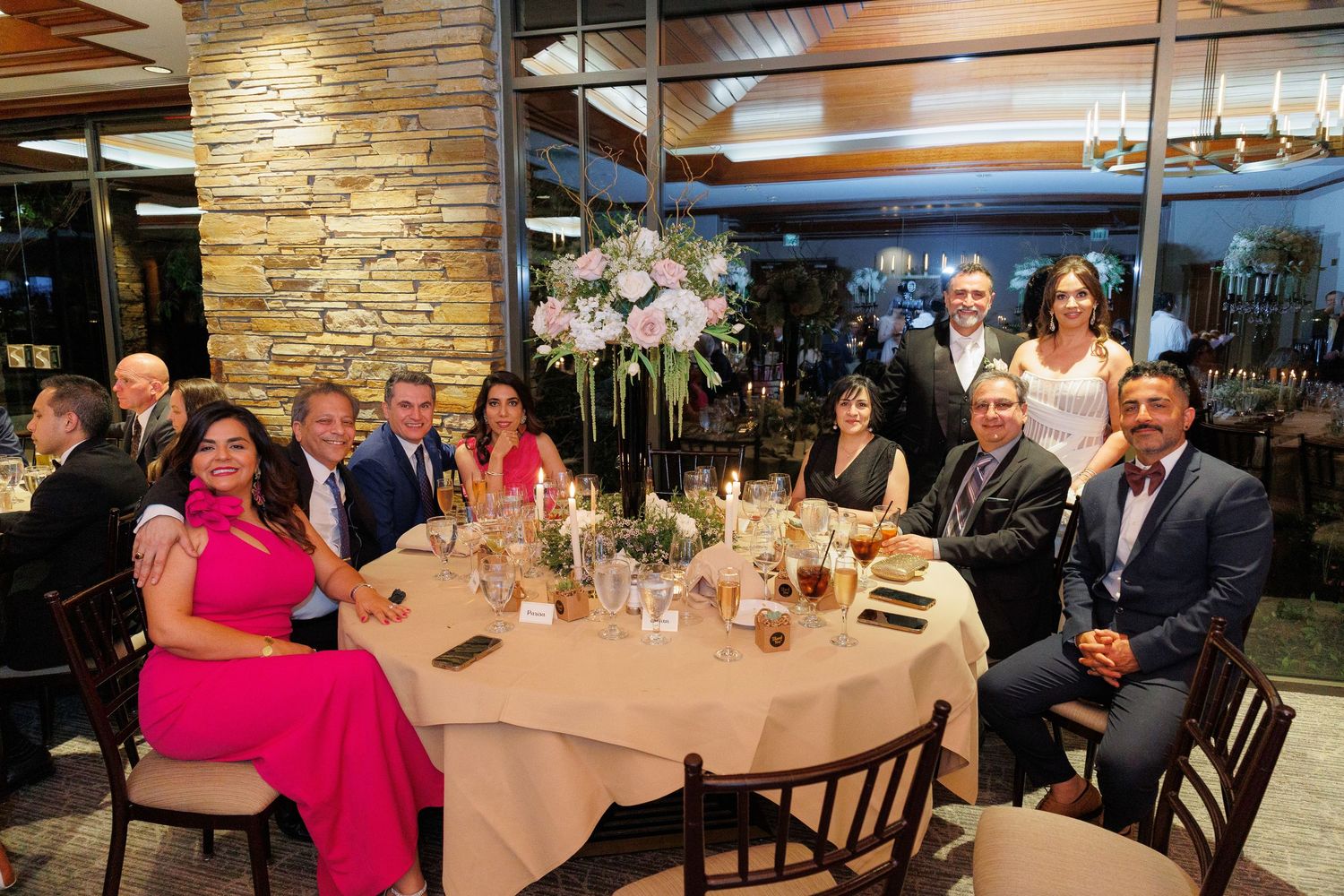 A panoramic view of a formal dining event with guests seated at elegantly decorated tables in a stone-walled restaurant.
