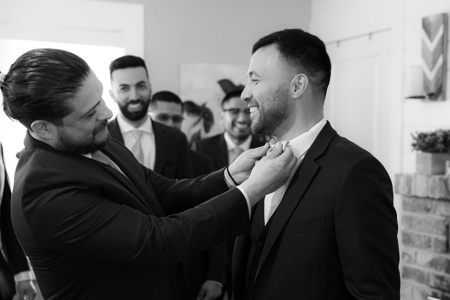 A black and white photo series showing candid moments of people laughing and embracing at a social gathering.