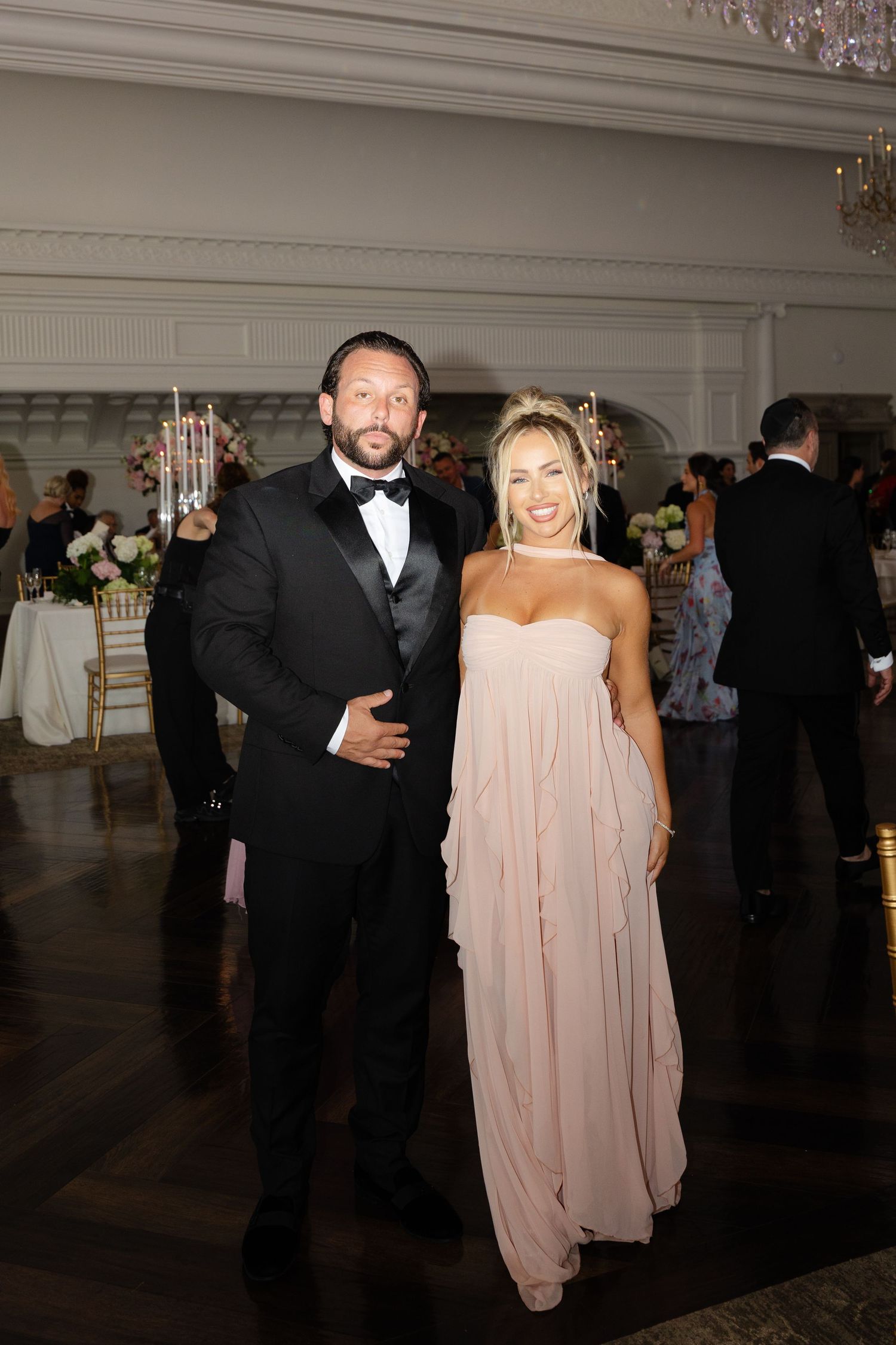 A couple in formal attire dancing together at a wedding reception in an elegant ballroom setting.
