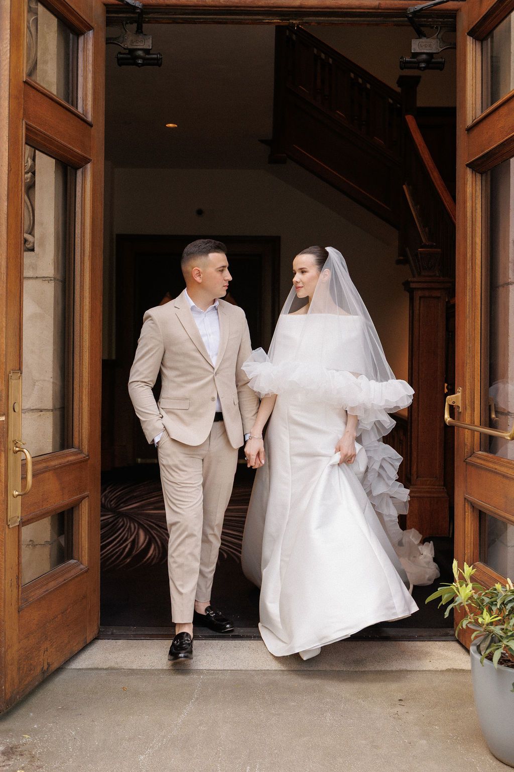 A bride and groom in white attire walk through wooden doors in a series of wedding photos.